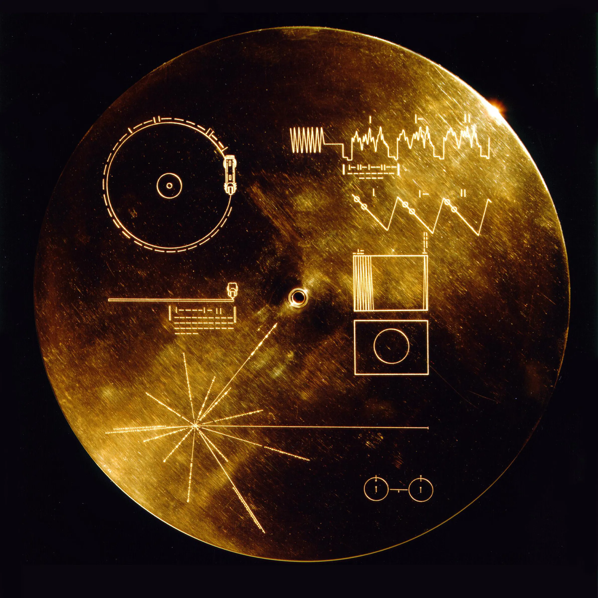 a circular golden record with various slightly cyrptic inscriptions on it