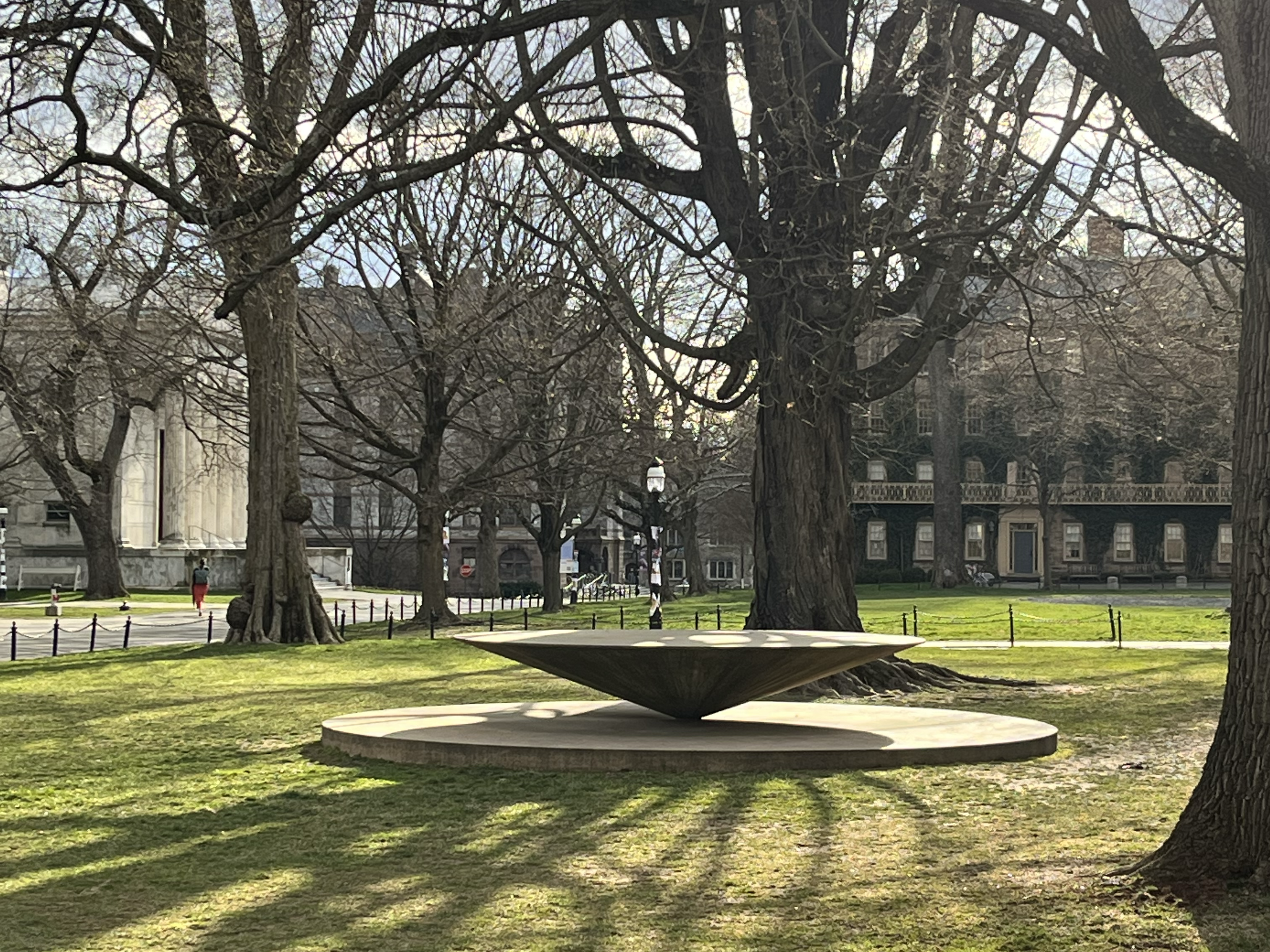 a cone stone table in an idyllic environment with trees and old university buildings